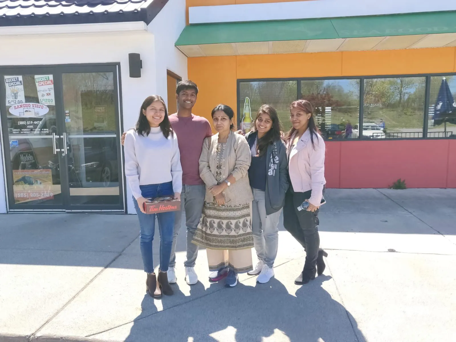 Group photo with friends outside a restaurant on a sunny day